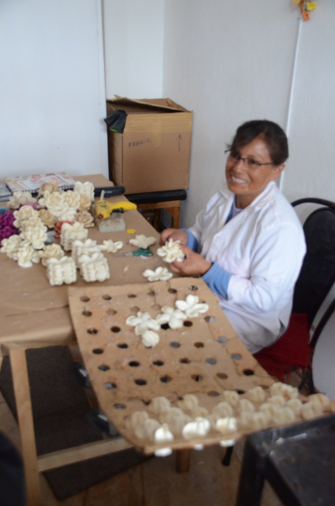 An employee makes flowers out of three pieces of material.  The flowers will be used on some types of hats.
