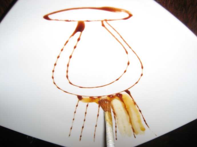 Step 3 -- The chef begins to paint the design using liquid caramel. 