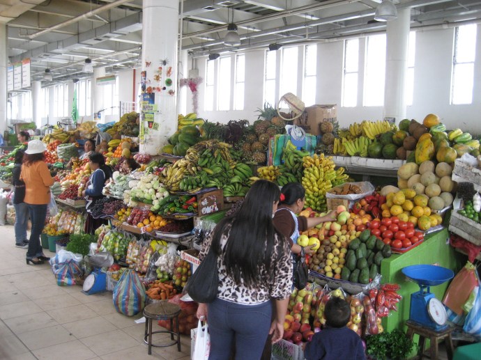 Two vendors in the market selling fruit to customers