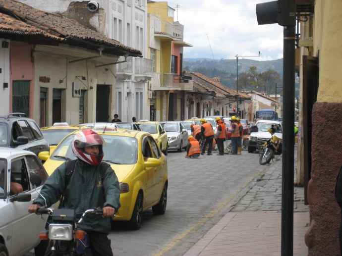 Here a road crew are replacing some paving bricks in the roadway.  No warning signs are posted for the oncoming traffic (to the left of the workers), nor are there safety barriers for the road workers.  Drivers just pay attention and avoid the workers in the road